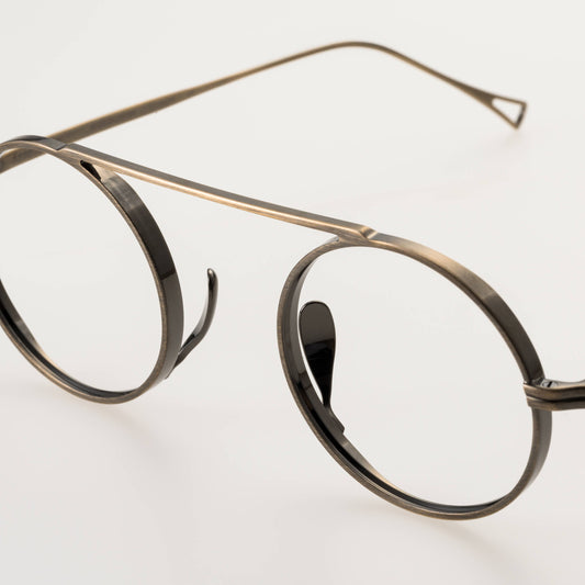 Round eyeglasses with gold frame on a light gray background